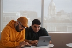 FILE - Iranian cybersecurity experts and members of Certfa Nariman Gharib, left, and Amin Sabeti check their messages as they work from their office in London, Britain, Jan. 7, 2020.