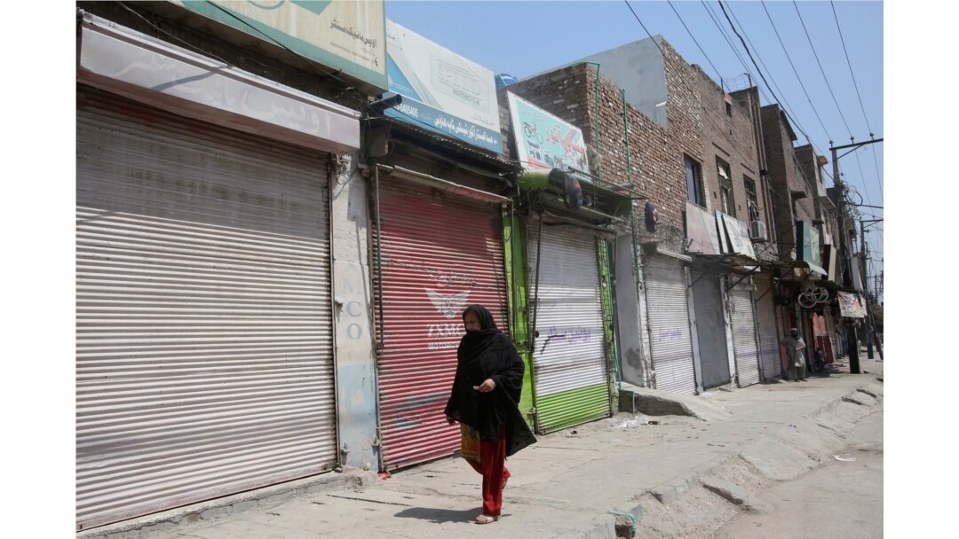 A woman walks past shops that are closed due to an escalation of cases of the coronavirus in Peshawar, Pakistan, June 17, 2020.