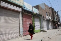 A woman walks past shops that are closed due to an escalation of cases of the coronavirus in Peshawar, Pakistan, June 17, 2020.