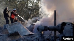 A member of Palestinian civil defense extinguishes a fire at a Hamas training camp after it was hit by an Israeli air strike in Khan Younis in the southern Gaza Strip, Dec. 24, 2013. 