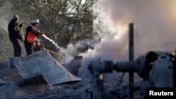 Đội dân vệ Palestine dập tắt lửa tại một trại huấn luyện của nhóm Hamas sau khi nơi này bị máy bay Israel oanh kích, 24/12/13
