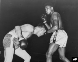 In this Oct. 29, 1960 file photo, Cassius Clay, in white trunks, is shown in his professional boxing debut, in Louisville's Freedom Hall against Tunney Hunsaker.