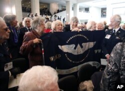 FILE - Members of the Women Airforce Service Pilots (WASP) hold up a flag on Capitol Hill in Washington after the ceremony where the first women in to fly America's military aircraft were awarded the Congressional Gold Medal, March 10, 2010.