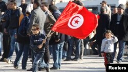 A Tunisian boy waves a flag during a rally in Tunis on December 17, 2013, marking the third anniversary of the Tunisian revolution.