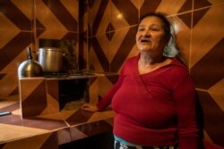 Maria da Silva shows her new wood stove to anyone who passes by her grocery store, in São Paulo, November 14, 2021. (Yan Boechat/VOA)
