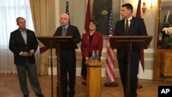 Latvian President Raimonds Vejonis (right) looks at US Sen. John McCain, (center left) during a press conference, Dec. 28, 2016, in Riga, Latvia, while Lindsey Graham, R-SC., and Amy Klobuchar, D-Minn., stand in the background. 