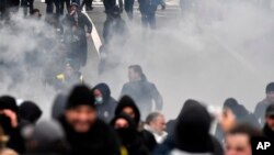 Polisi anti huru hara menggunakan gas air mata untuk membubarkan demonstran selama protes terhadap tindakan virus corona, di Brussels, Belgia, 5 Desember 2021. (Foto: AP)