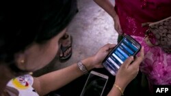 This photograph taken on September 22, 2019 shows Myanmar information technology volunteers assisting a mobile phone user switching from the old Zawgyi font to the unicode font in Yangon. - Accessing everything from Wikipedia to Google Maps in Myanmar is 