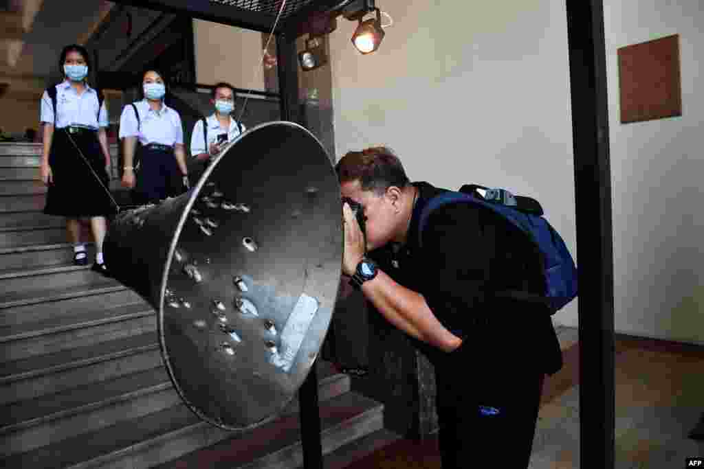 A man takes a photo of a loudspeaker ridden with bullet holes during the Thammasat University massacre on October 6, 1976, at an exhibition commemorating the event at Thammasat University in Bangkok, Thailand.