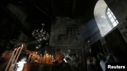 Visitors light candles in the Church of the Nativity ahead of Christmas in the West Bank town of Bethlehem, Dec. 23, 2013. 