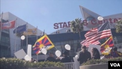 藏人在洛杉磯湖人隊的史鐵波斯中心前高舉美國和西藏旗幟示威﹐紀念抗暴。(視頻截圖)