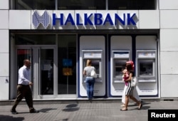 FILE - A customer uses an automated teller machine at a branch of Halkbank in Istanbul, Aug. 15, 2014.