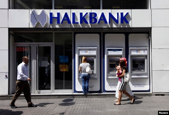 FILE - A customer uses an automated teller machine at a branch of Halkbank in Istanbul, Aug. 15, 2014.