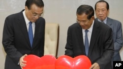 China's Premier Li Keqiang, left, pulls a symbol of China-Cambodia Heart Journey, together with his Cambodian counterpart Hun Sen, center, during a signing ceremony at Peace Palace in Phnom Penh, Cambodia, Thursday, Jan. 11, 2018. Cambodia and China on Thursday signed nearly 20 agreements worth several billion dollars to develop the impoverished Southeast Asian country's infrastructure, agriculture and healthcare. (AP Photo/Heng Sinith)
