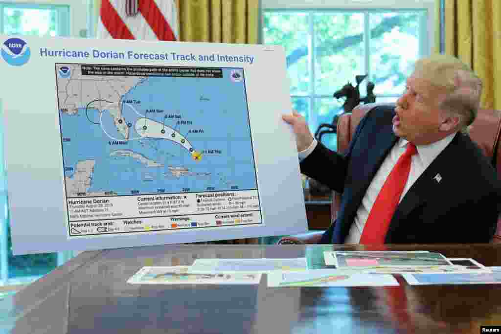 U.S. President Donald Trump holds a chart showing the projected track of Hurricane Dorian that appears to have been extended with a black line to include parts of the Florida panhandle and of the state of Alabama during a status report meeting on the hurricane in the Oval Office of the White House in Washington, Sept. 4, 2019.