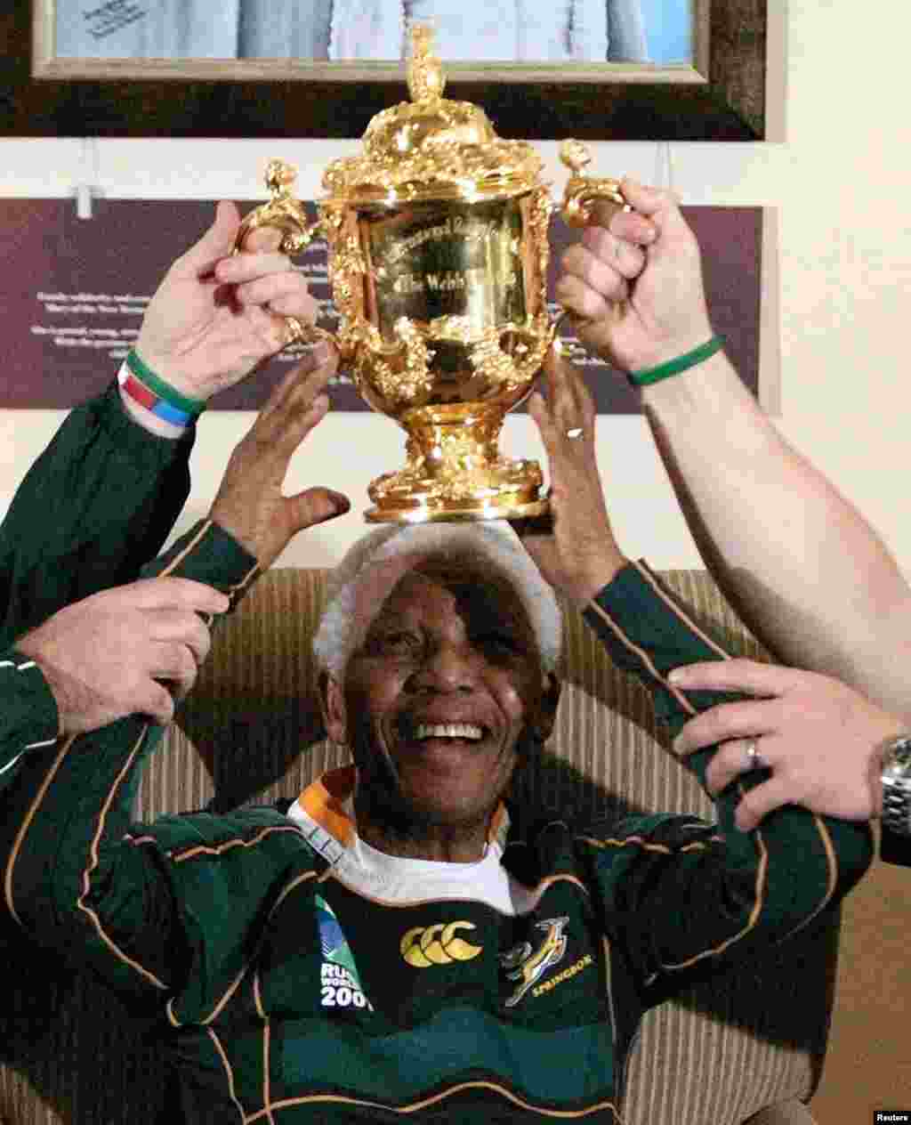 L&#39;ancien président sud-africain Nelson Mandela souriant et aidé, soulève le trophée Webb Ellis qui lui a été présenté par les Springboks à la Fondation Mandela à Houghton Octobre 27, 2007.