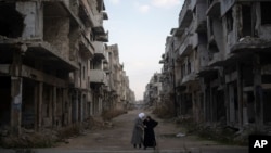 FILE - Women talk on a street surrounded by buildings that were destroyed during the civil war at the district of Khalidiya in Homs, Syria, Jan. 1, 2025.