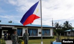 FILE - Filipino soldiers stand at attention near a Philippine flag at Thitu island in disputed South China Sea, April 21, 2017.