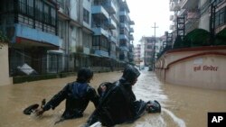 FILE - A Nepalese pulls his motorbike and wades past a flooded street in Kathmandu, Nepal, July 12, 2019. 