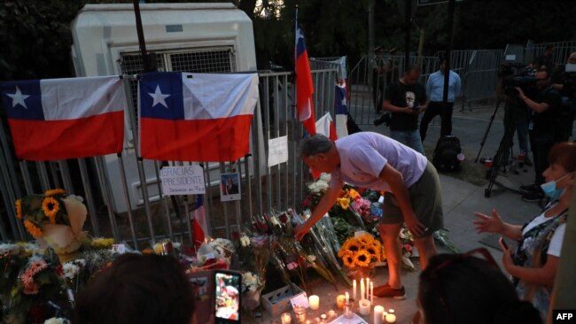 Chilenos dejan velas, flores y banderas frente a la casa del expresidente Sebastián Piñera en Santiago, el 6 de febrero de 2024.