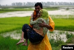 A local man carries an old Rohingya refugee woman as she is unable to walk after crossing the border, in Teknaf, Bangladesh, Sept. 1, 2017.