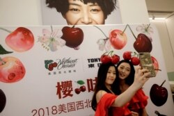 FILE - Models take a selfie during a promotional event of Northwest Cherries from the United States at a shopping mall in Shenzhen, China, July 8, 2018.