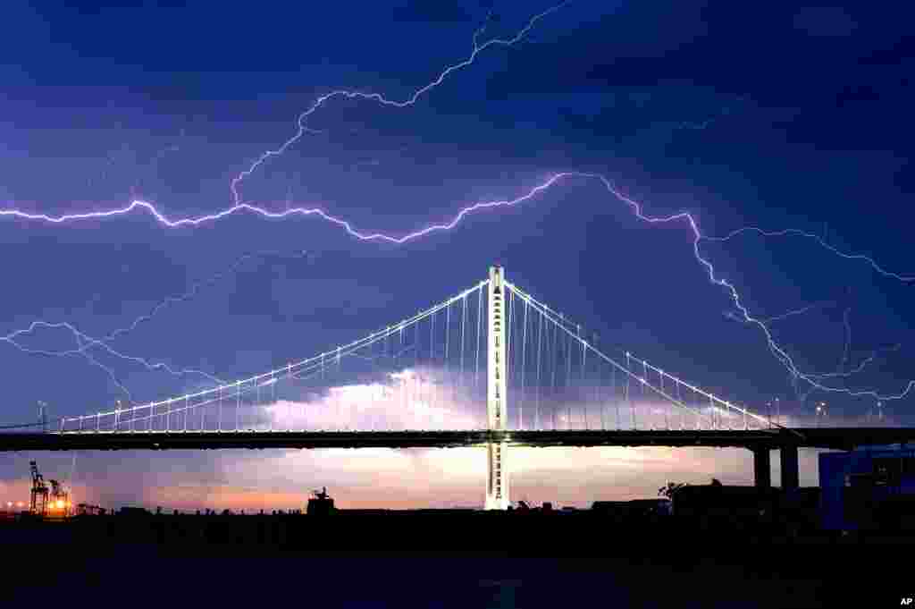 Lightning forks over the San Francisco-Oakland Bay Bridge as a storm passes over Oakland, California.