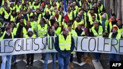 Yellow Vests (Gilets jaunes) march behind a banner reading "Yellow vests are angry" as they protest high fuel prices in Rochefort, southwestern France, Nov. 24, 2018, part of a movement which has spread into a widespread protest against stagnant spending