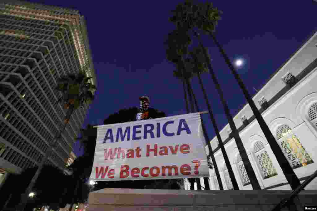 A man holds a sign reading &quot;AMERICA What Have We Become?&quot; during a protest against the impeachment acquittal of U.S. President Donald Trump outside city hall in Los Angeles, California, Feb. 5, 2020.