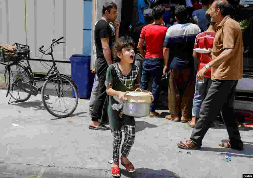 A girl carries food distributed by a charitable organization in Mosul, Iraq, Aug. 10, 2021.