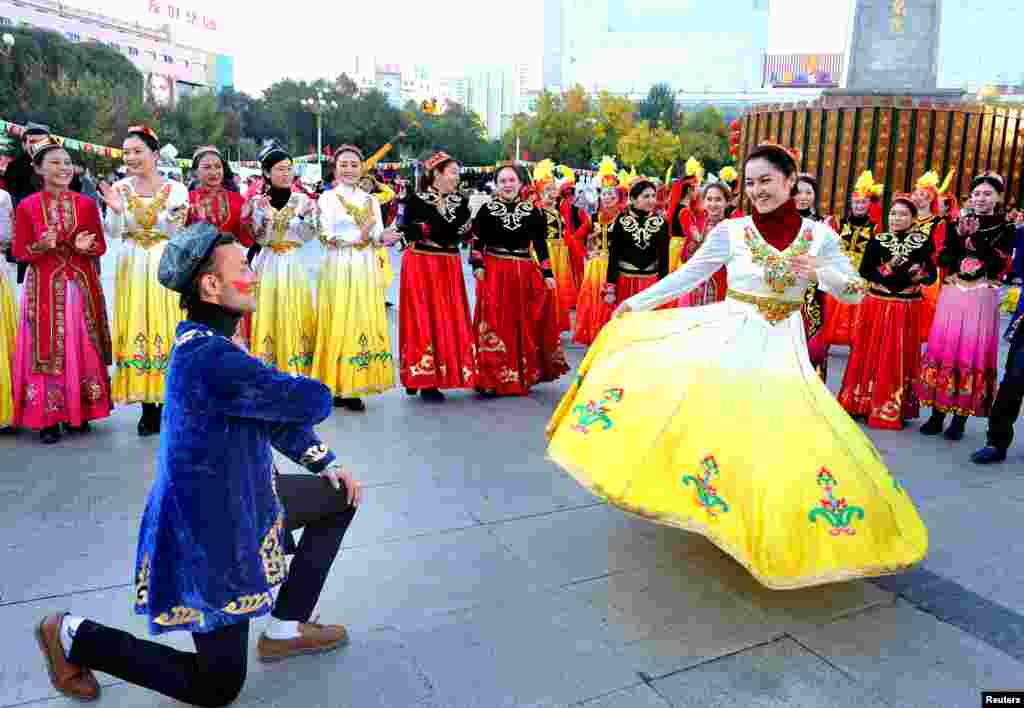 ប្រជាជនធ្វើការសម្តែងនៅទីលានមួយអំឡុងពេលអបអរសាទរខួបទី ៦០នៃការបង្កើតតំបន់ស្វយ័តអ៊ុយហ្គរ (Uighur) នៅក្រុង Urumqi។