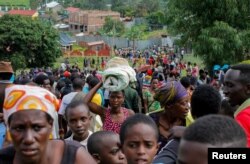 FILE - Refugees from the Democratic Republic of Congo carry their belongings as they walk near the United Nations High Commissioner for Refugees (UNHCR) offices in Kiziba refugee camp in Karongi District, Rwanda, Feb. 21, 2018.