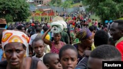 Refugees from the Democratic Republic of Congo carry their belongings as they walk near the United Nations High Commissioner for Refugees (UNHCR) offices in Kiziba refugee camp in Karongi District, Rwanda, Feb. 21, 2018.