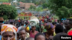 FILE - Refugees from the Democratic Republic of Congo carry their belongings as they walk near the United Nations High Commissioner for Refugees offices in Kiziba refugee camp in Karongi District, Rwanda, Feb. 21, 2018.