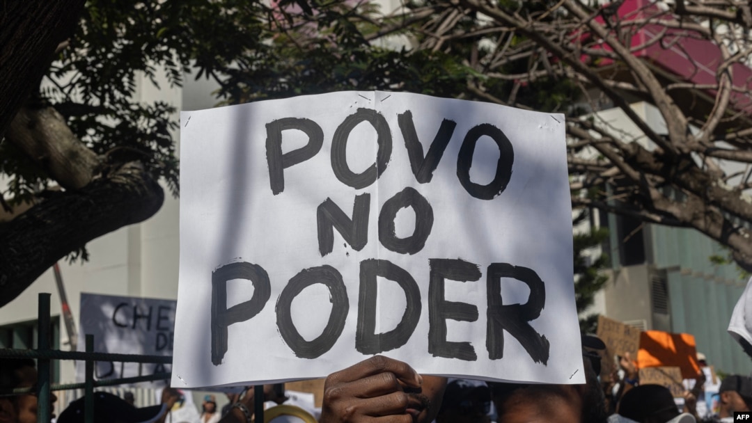 Um homem segura uma faixa com a inscrição “poder do povo” durante a reunião que antecede a marcha convocada por membros da comunidade islâmica moçambicana contra os resultados das eleições presidenciais de 2024, em Maputo, a 2 de novembro de 2024.