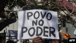 Um homem segura uma faixa com a inscrição “poder do povo” durante a reunião que antecede a marcha convocada por membros da comunidade islâmica moçambicana contra os resultados das eleições presidenciais de 2024, em Maputo, a 2 de novembro de 2024.