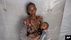 Tigrinyan refugee 38-year-old Rega Tsfay, malnourished mother of her 3-moth-old son Itbarak, stands for a photograph inside a tent, in Umm Rakouba refugee camp in Qadarif, eastern Sudan, Dec. 10, 2020. 