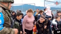 در این تصویر که از یک ویدئوی بخش مطبوعاتی وزارت دفاع روسیه در ۳۰ شهریور گرفته شده است، یک نیروی حافظ صلح روسی با ارمنی‌ها که از دروازه‌ یک کمپ در قره‌باغ کوهستانی عبور می‌کنند، صحبت می‌کند. هزاران نفر از ساکنان قره باغ کوهستانی برای در امان ماندن از درگیری به این کمپ هجوم بردند.