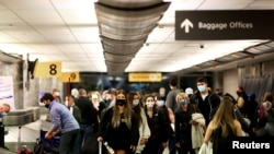 FILE PHOTO: Travelers wearing protective face masks to prevent the spread of the coronavirus disease reclaim their luggage at the airport in Denver, Colorado, Nov. 24, 2020.