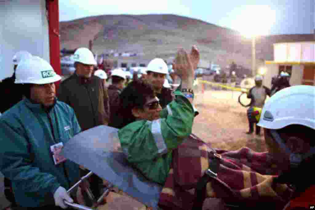 In this photo released by the Chilean government, miner Claudio Yanez applauds as he is carried away in a stretcher after being rescued from the collapsed San Jose gold and copper mine where he had been trapped with 32 other miners for over two months nea