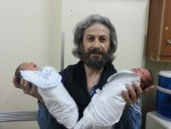 Foad Ahmed el-Mohamed, was a local journalist in Deir el-Zour. Here holding a twin born in the hospital he used to work at in 2014. (Photo courtesy Ensaf Nasser)