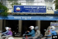 FILE - Cambodians ride motorbikes past the hardquarters of the Cambodia National Rescue Party (CNRP) in Phnom Penh on October 6, 2017. The Cambodian government on October 6 asked the country's top court to dissolve the embattled opposition party whose leader has been thrown in jail for alleged treason charges, lawyers said. (Photo by TANG CHHIN SOTHY / AFP)