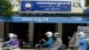 FILE PHOTO - Cambodians ride motorbikes past the headquarters of the Cambodia National Rescue Party (CNRP) in Phnom Penh on October 6, 2017. (Photo by TANG CHHIN SOTHY / AFP)