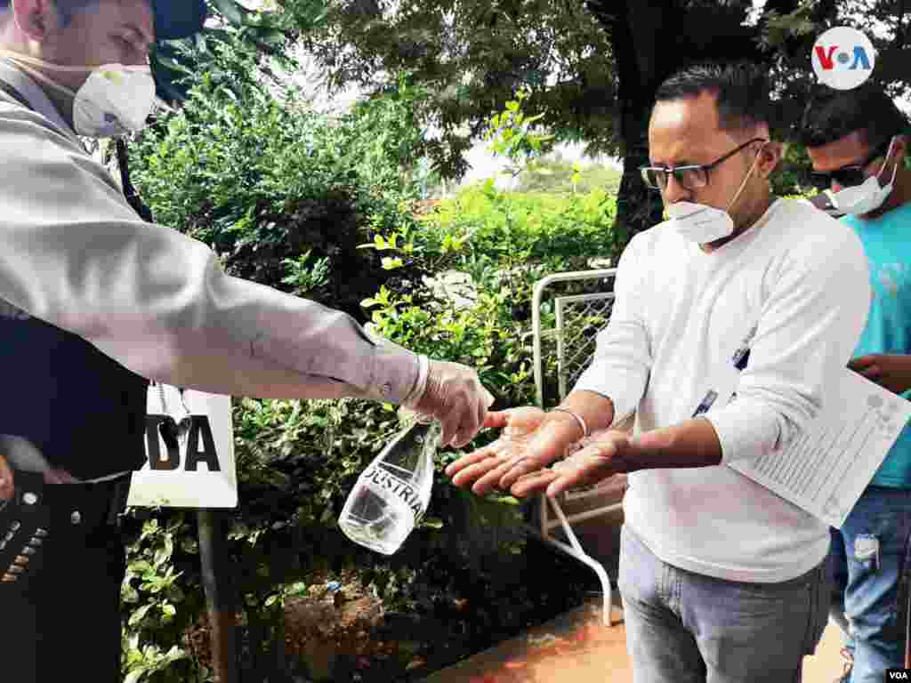 Personal sanitario limpia las manos de un migrante con un gel antibacterial para desinfectar.