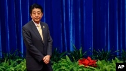 FILE - Japan's Prime Minister Shinzo Abe wait to meet China's President Xi Jinping, during their meeting at the Great Hall of the People, on the sidelines of the Asia Pacific Economic Cooperation (APEC) meetings, in Beijing, Nov. 10, 2014.