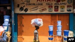 Un homme avec sa marchandise sur sa tête passe devant un magasin fermée au Marché Central, à Kinshasa, le 8 juillet 2016.