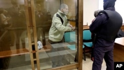 In this photo released by the Moscow City Court Press Service, Stephen Hubbard, a U.S. citizen accused of fighting as a mercenary in Ukraine stands in a glass cage during a court session in Moscow, Oct. 7, 2024.