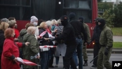 People, most of them elderly women, argue with plainclothes policemen during an opposition rally to protest the official presidential election results in Minsk, Belarus, Oct. 12, 2020.