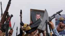 Seorang pengunjuk rasa memegang poster pemimpin Houthi Abdul-Malek al-Houthi, sementara lainnya mengangkat senjata dalam aksi mendukung warga Palestina di Jalur Gaza di tengah konflik Israel-Hamas, Sanaa, Yaman, 26 Juli 2024. (Foto: Reuters)