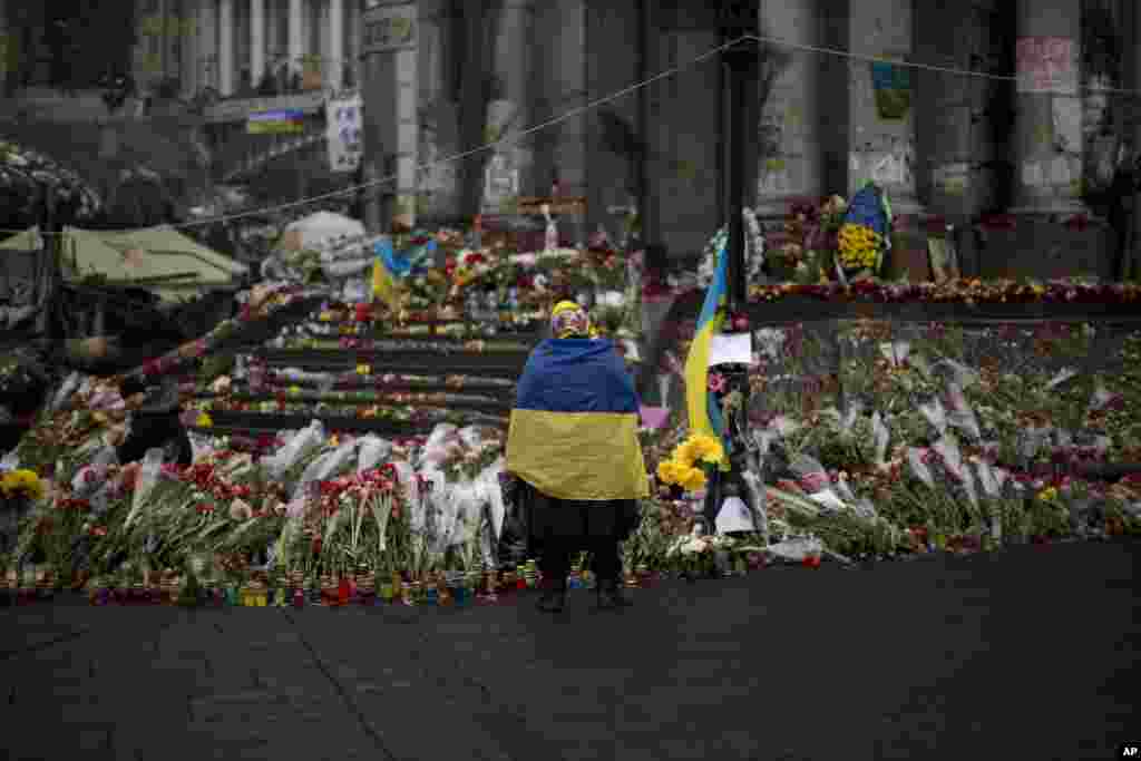 A woman wearing a Ukrainian flag stands at a memorial for people killed in clashes with the police at Kyiv's Independence Square, March 3, 2014. 